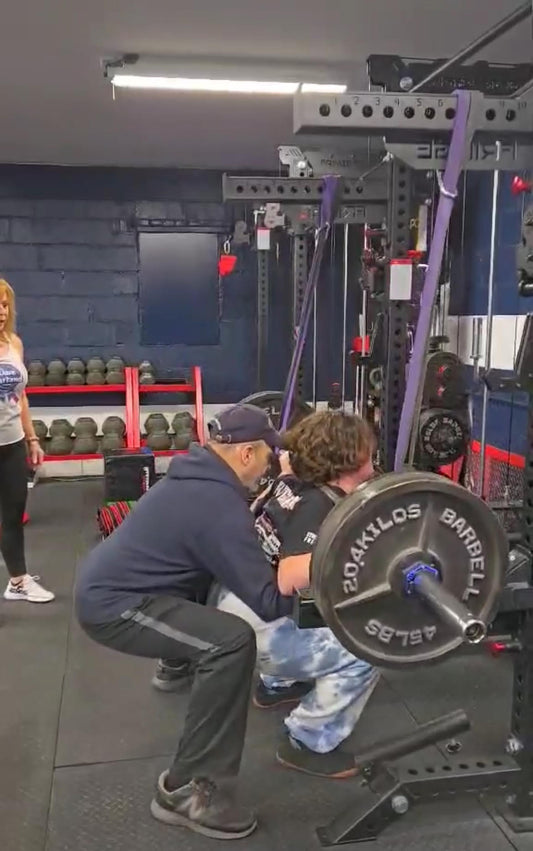 Powerlifter performing a 315-pound squat with coach spotting, symbolizing strength, perseverance, and growth
