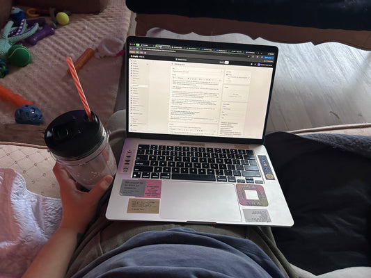 photo of laptop in the writers lap while holding a protein shake