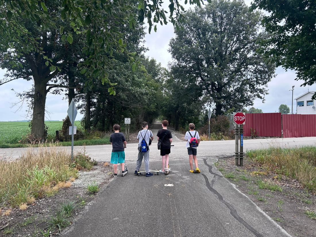 Four teenage boys talking while walking down a bike trail. 